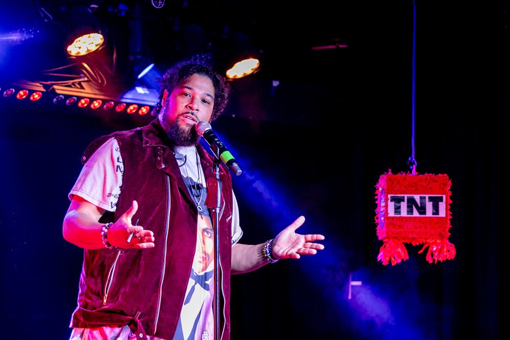 Comedian at the mic beside the TNT piñata