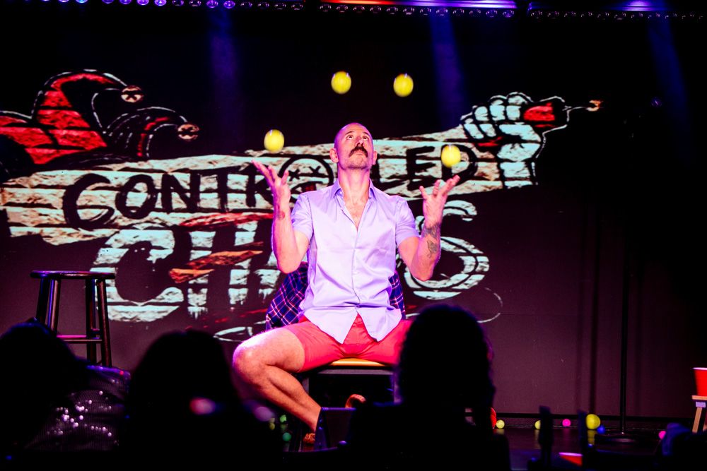 Juggler on stage in front of the Controlled Chaos logo